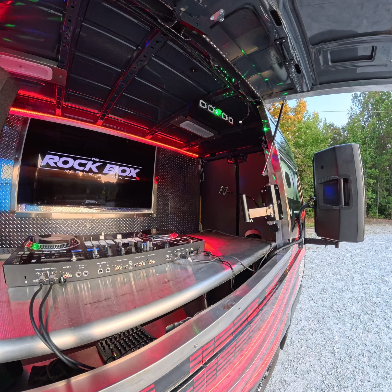 The Rock Box DJ van with rear doors open showing the speaker system and LED-lit stage